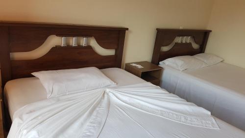 a bedroom with two beds with white sheets at Hotel Ocean View & Restaurante Seafood in São Filipe