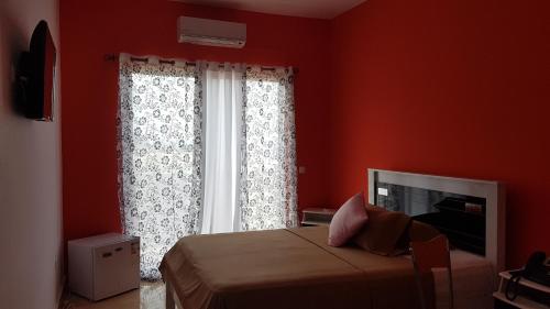 a red bedroom with a bed and a window at Hotel Ocean View & Restaurante Seafood in São Filipe
