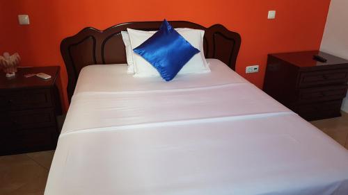 a bed with a blue pillow on top of it at Hotel Ocean View & Restaurante Seafood in São Filipe