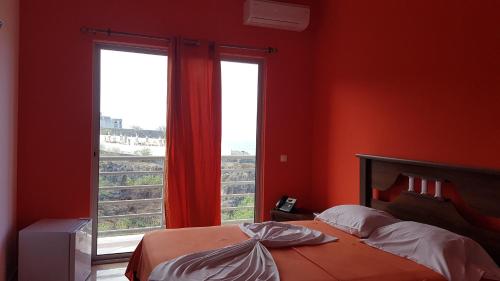 a bedroom with red walls and a bed and two windows at Hotel Ocean View & Restaurante Seafood in São Filipe