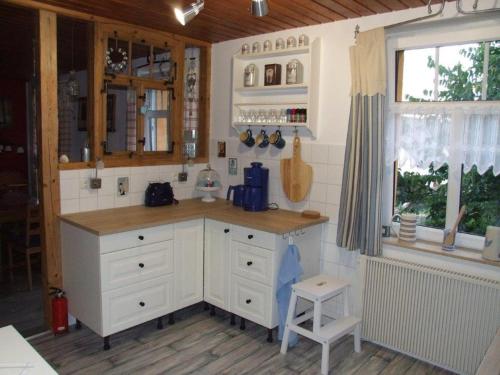 a kitchen with white cabinets and a counter with a window at Schluchthäusl in Lunzenau