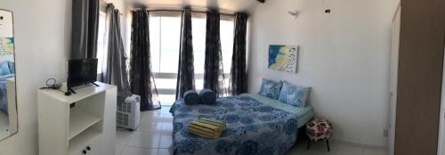 a living room with a blue chair and a television at Casa em Condomínio Barra São Miguel in Barra de São Miguel