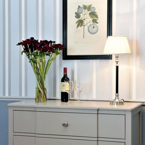 a table with a vase of flowers and a bottle of wine at Hotel Kärntnerhof in Vienna