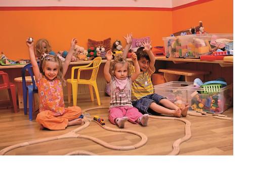 three little girls sitting on the floor with their hands in the air at Saaserhof Apartments in Saas-Fee