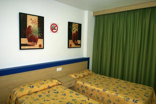 a hotel room with two beds and green curtains at Apartamentos Paraiso 10 in Benidorm