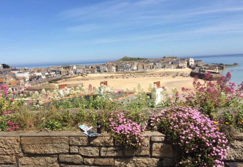a view of a beach from a wall with flowers at 11 longstone house in Carbis Bay