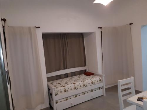 een kleine slaapkamer met een wit bed en gordijnen bij Cabaña Siete Colores in Santa Rosa de Calamuchita