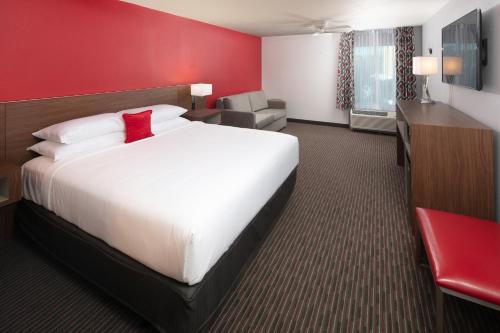 a hotel room with a large bed and a red wall at Red Lion Hotel Orlando Lake Buena Vista South- Near Disney in Kissimmee