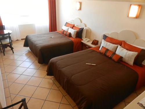a hotel room with two beds and a table at Hotel 9 Manantiales in Chignahuapan