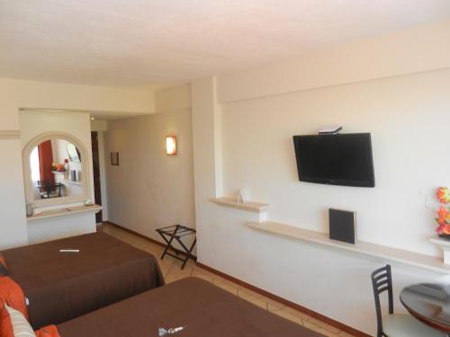a hotel room with a bed and a flat screen tv at Hotel 9 Manantiales in Chignahuapan