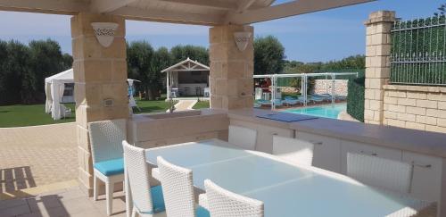 un patio con tavolo, sedie e piscina di Appartamenti in villa Alessia a Monopoli