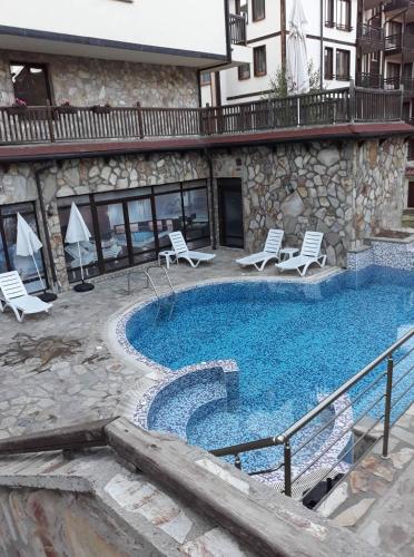 Una gran piscina con sillas y un edificio. en Mountain Top Mina, en Bansko
