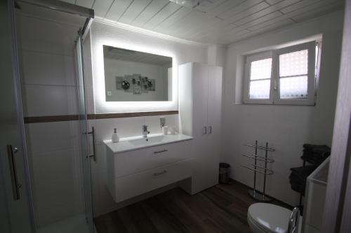 ein weißes Badezimmer mit einem Waschbecken und einem Spiegel in der Unterkunft Milonia in Bernkastel-Kues