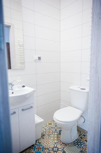 a white bathroom with a toilet and a sink at Ahoj Apartments in Ustka