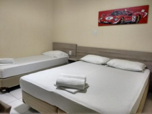 two beds in a room with a car painting on the wall at Hotel Ville House Premium in Canoas