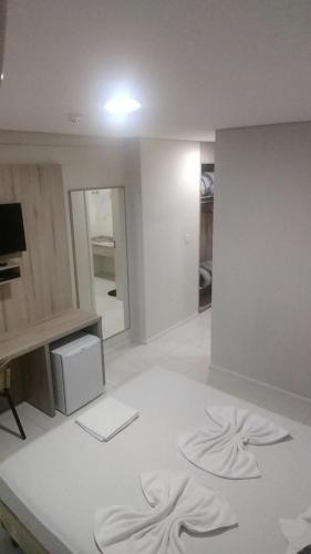 a living room with a white floor and a mirror at Hotel Ville House Premium in Canoas