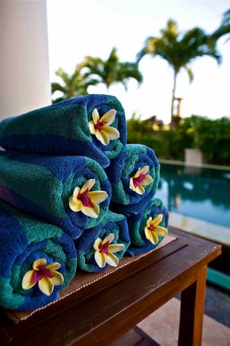 a stack of towels with flowers on a table at Villa Padi in Canggu
