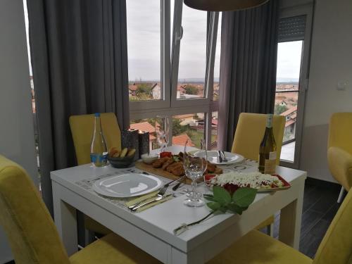 a table with a plate of food and a window at Apartman Karma in Bijeljina