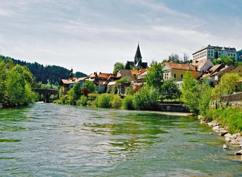 a river in a town with a bridge and buildings at Panorama Apartment Bauernhof Mandl in Murau