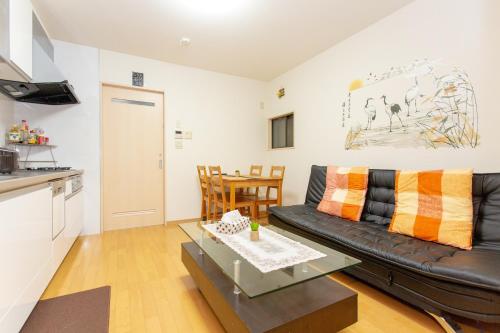 a living room with a black leather couch and a table at City Center House Next to Subway Station in Kyoto