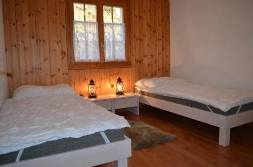 Duas camas num quarto com paredes e janelas de madeira em Malva em Belalp