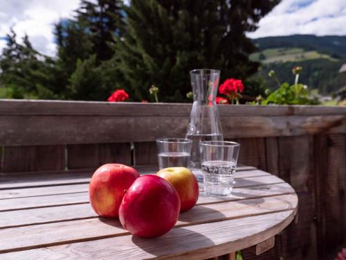 a wooden table with three apples and glasses on it at Landhaus Strickenmacher in Sillian