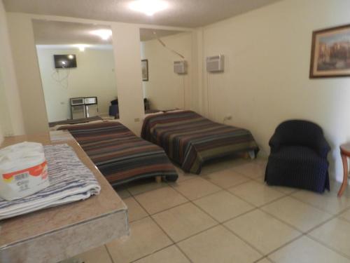 una habitación de hotel con 2 camas y una silla en Consul Suites, en Ciudad Juárez