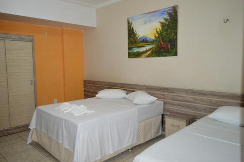Habitación con 2 camas y una pintura en la pared. en Pousada Ayrumã en Itapipoca
