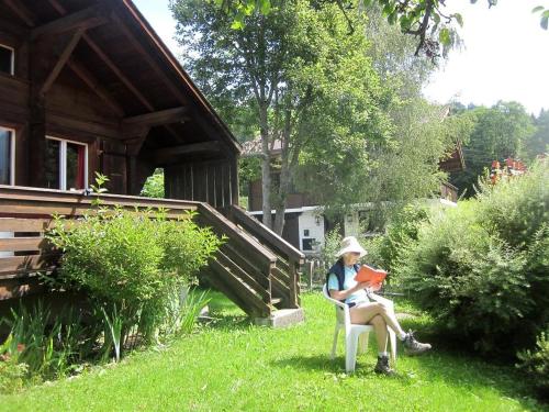 a woman sitting in a chair reading a book at Apartment Minnehaha- Chalet by Interhome in Lauenen