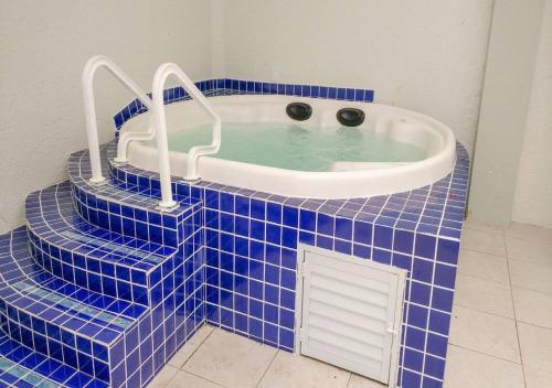 een blauwe betegelde badkamer met een jacuzzi bij Apartamento Classe A in Florianópolis