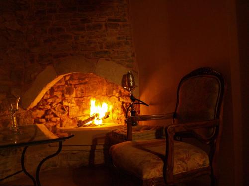 a stone fireplace with a chair and a fire place at DonQuihotel Chalet in Karvounádhes