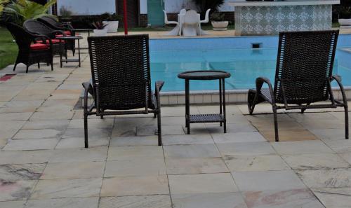 a group of chairs and a table next to a pool at Pousada La Maison in Iguaba Grande