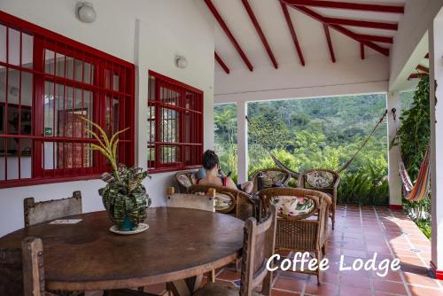 a dining room table with chairs and a window at Hacienda Venecia Coffee Farm Hotel in Manizales