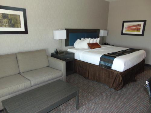 a hotel room with a bed and a couch at Wingate by Wyndham Lubbock in Lubbock
