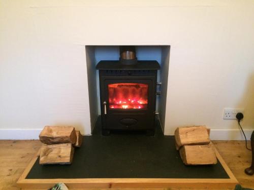 a stove in a room with two logs at Ardminish House Gigha in Isle of Gigha