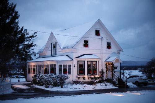 a white house with christmas lights in the snow at CARLETON INN & COTTAGES in Bridgetown
