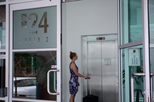 a woman standing outside of a building with a suitcase at Auckland Waterfront Serviced Apartments on Prince's Wharf in Auckland