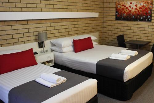2 camas en una habitación con almohadas rojas y blancas en Golden Harvest Motor Inn Moree, en Moree