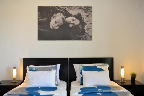 a bedroom with two beds and a painting on the wall at Guesthouse Le Châtelain in Santa Maria