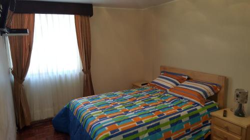 a bedroom with a bed with a colorful comforter and a window at Lujoso departamento in Quito