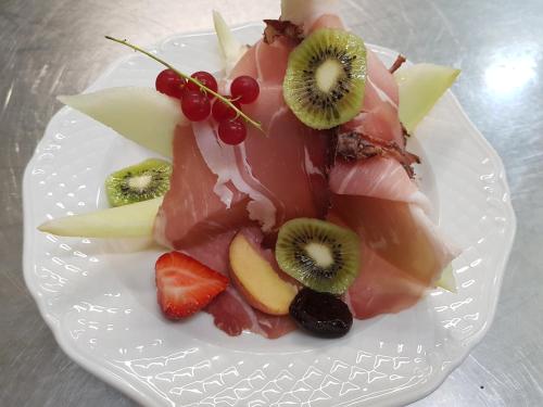 a white plate topped with fruit on a table at Hotel zur Waage in Bad Münstereifel