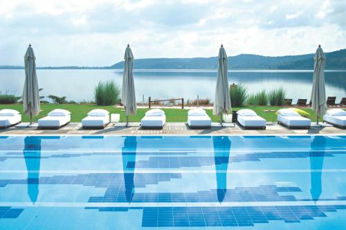 a swimming pool with umbrellas and a body of water at Richmond Nua Wellness Spa - Adult Only in Sapanca