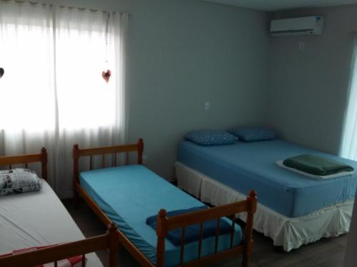 2 camas en una habitación pequeña con ventana en Residencial Corrêa, en Penha