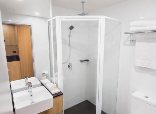 a white bathroom with a shower and a sink at Ibis Styles Hobart in Hobart