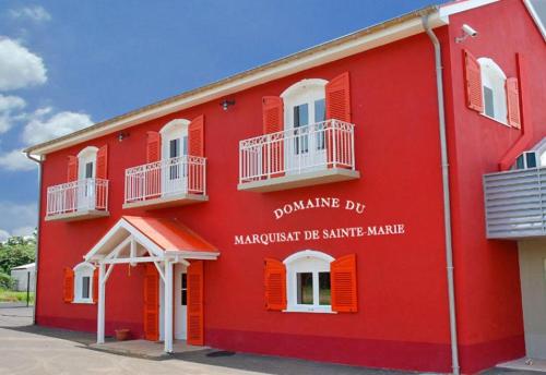 a red building with orange shutters on it at Tigili l'Appart Lagon in Capesterre-Belle-Eau