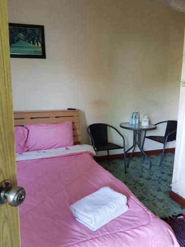 1 dormitorio con 1 cama rosa, mesa y sillas en สบาย สบาย รีสอร์ท, en Ban Khao San