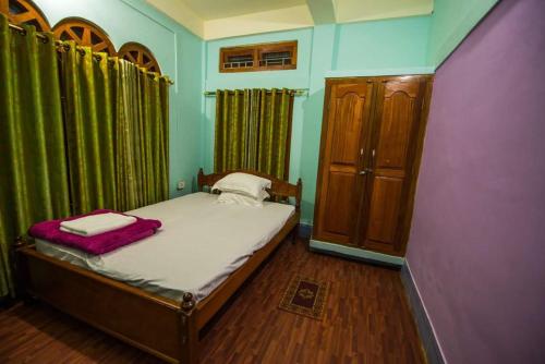 um pequeno quarto com uma cama e cortinas verdes em VAMOOSETRAIL PASIGHAT(1) em Pasighat