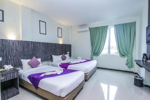 two beds in a hotel room with green curtains at Salsa Resort Langkawi By Casa Loma in Pantai Cenang