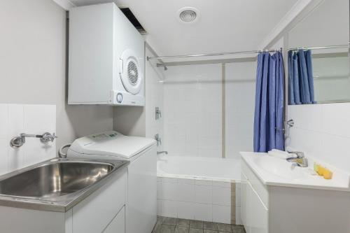 a small white bathroom with a sink and a shower at Nesuto The Entrance in The Entrance