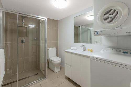 a bathroom with a shower and a toilet and a sink at Nesuto The Entrance in The Entrance